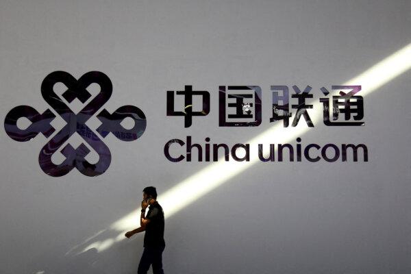 A man holding a mobile phone walks past a China Unicom logo during the Mobile World Congress in Shanghai, China, on June 28, 2023. (Nicoco Chan/Reuters)