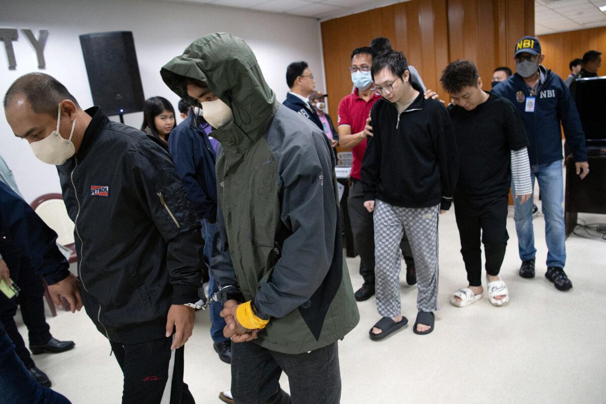 The Chinese nationals (background 3rd R and second R) and their suspicious Filipino accomplices (L and second L) have been arrested on suspicion of spying and are escorted from the room by National Bureau of Investigation (NBI) agents after a press conference at the NBI office held in Manila on February 25, 2025.