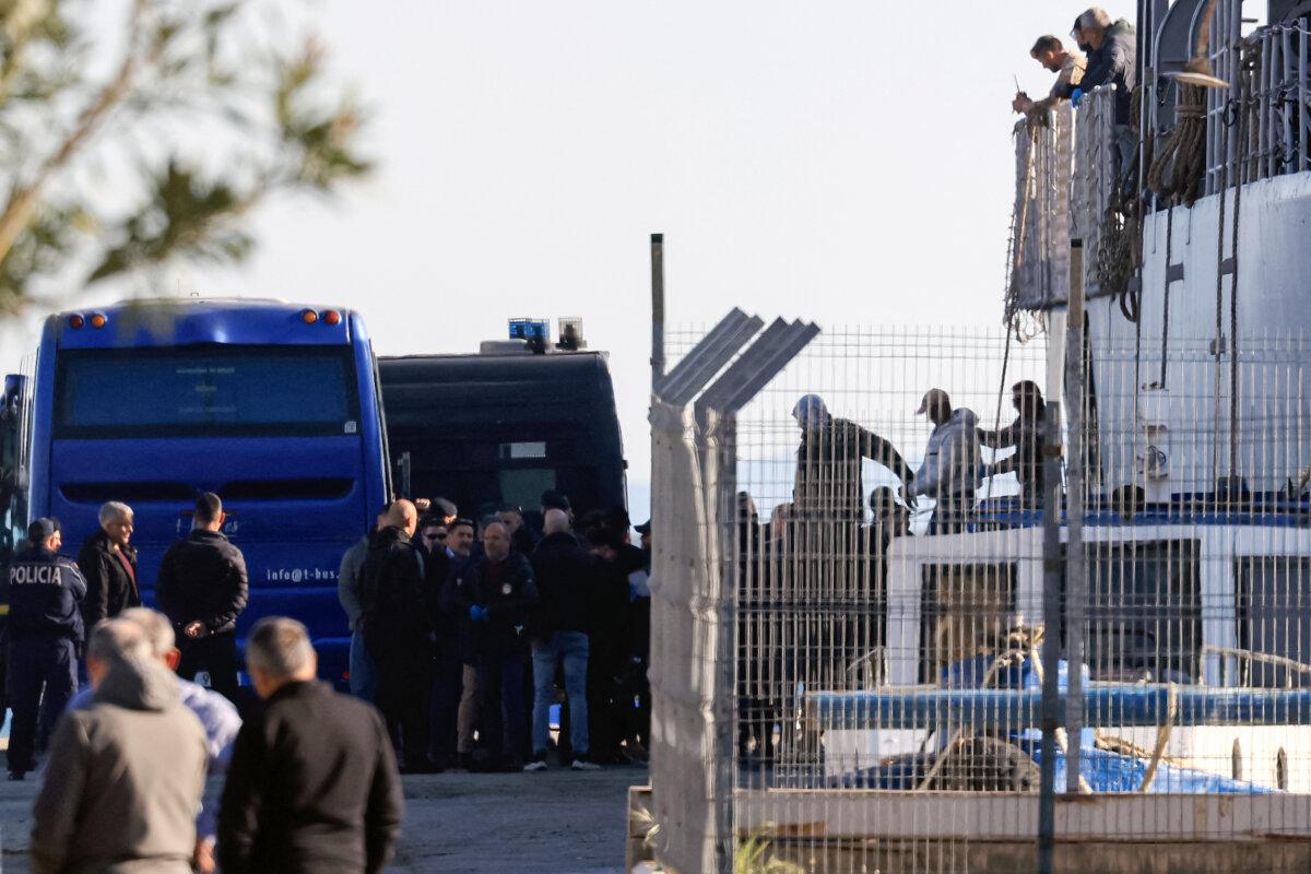 Migrants from various detention centers across Italy are escorted by police as they disembark an Italian Navy vessel at the port of Shengjin, Albania, on April 11, 2025. (Adnan Beci/AFP via Getty Images)