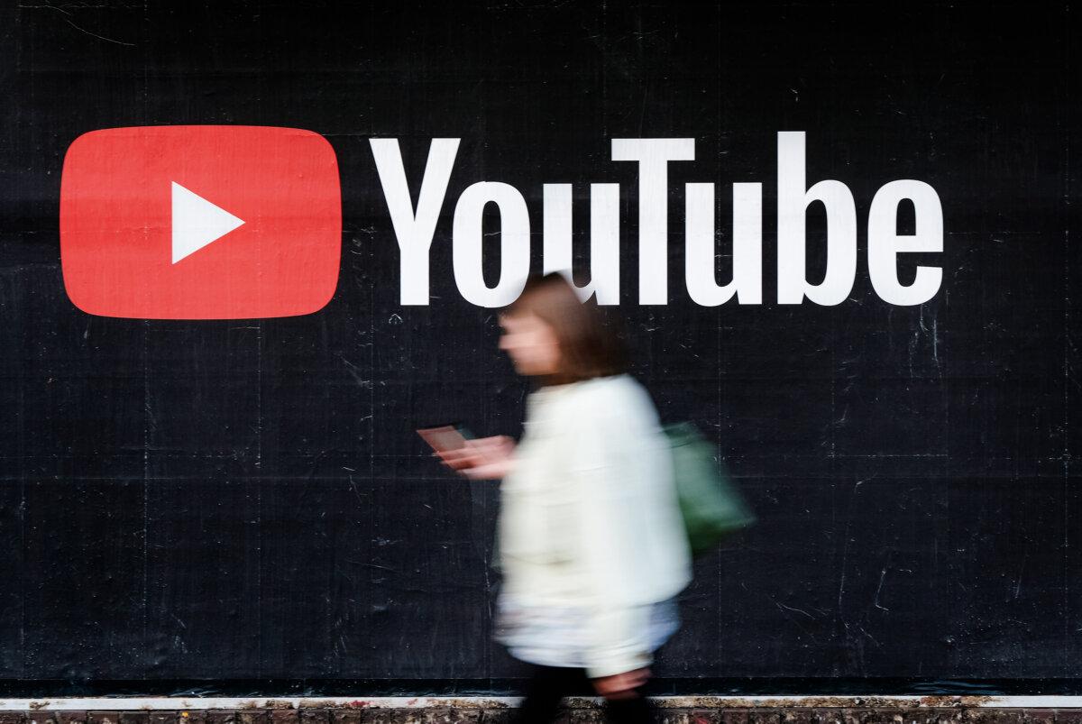 A young woman with a smartphone walks past a billboard advertisement for YouTube in Berlin, Germany, on Sept. 27, 2019. (Sean Gallup/Getty Images)