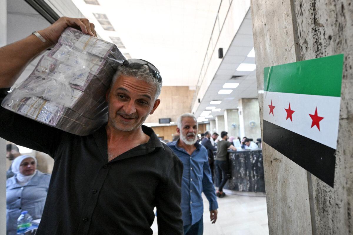 A man carrying a stash of Syrian pounds leaves the central bank in Damascus on May 21, 2025. (Louai Beshara/AFP via Getty Images)