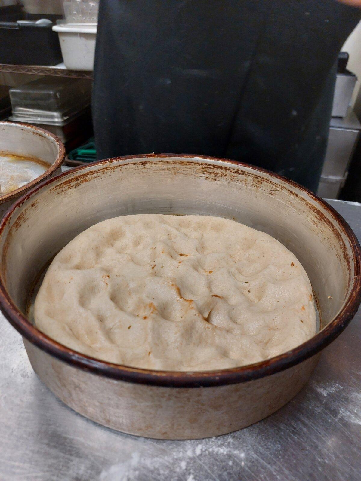 With lightly oiled hands, smoosh the dough down and spread it into the edges of the pan. (Kevin Revolinski)