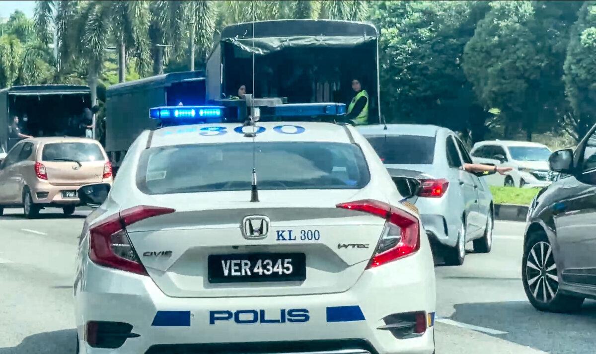 Malaysian police cars escort vans holding Falun Gong practitioners, in Kuala Lumpur, Malaysia, on April 13, 2025. (The Epoch Times)
