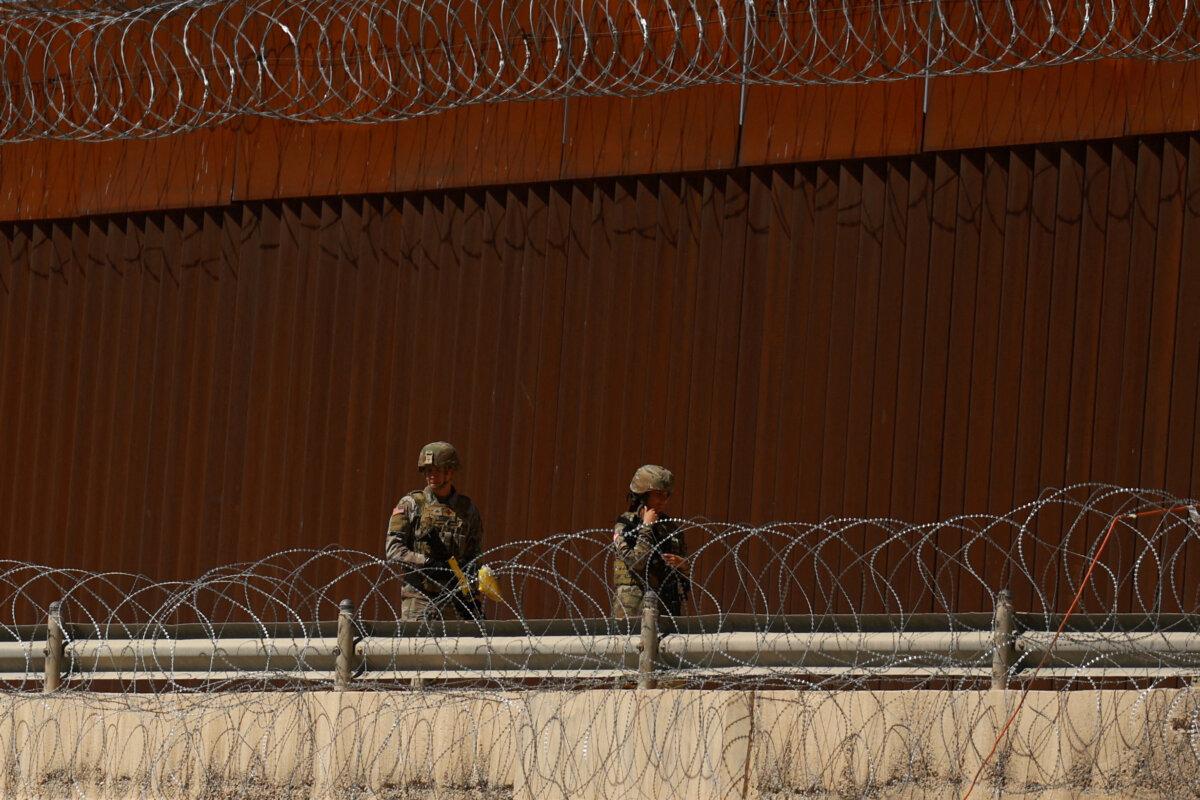 Texas National Guard soldiers walk near the U.S.-Mexico border wall, as seen from Ciudad Juarez, Mexico, on March 11, 2025. (Jose Luis Gonzalez/Reuters)