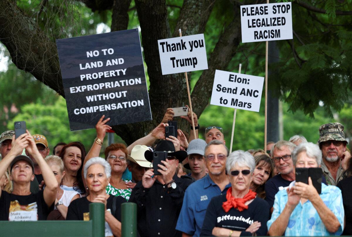 Demonstrators hold placards in support of U.S. President Donald Trump's stance against what he calls racist laws, land expropriation, and farm attacks, outside the American Embassy in Pretoria, South Africa, on Feb. 15, 2025. (Siphiwe Sibeko/Reuters)