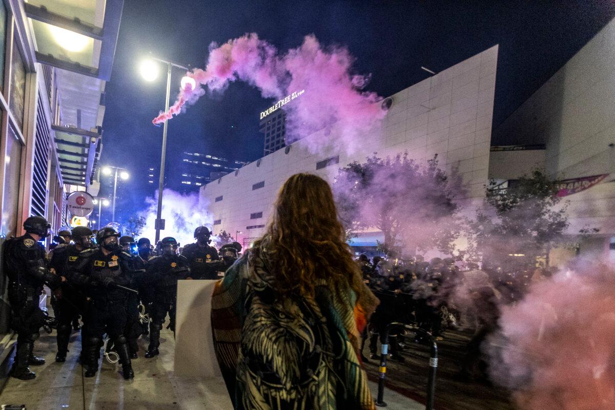 A smoke bomb arcs over a police line in Los Angeles on June 9, 2025. (Ringo Chiu/AFP via Getty Images)