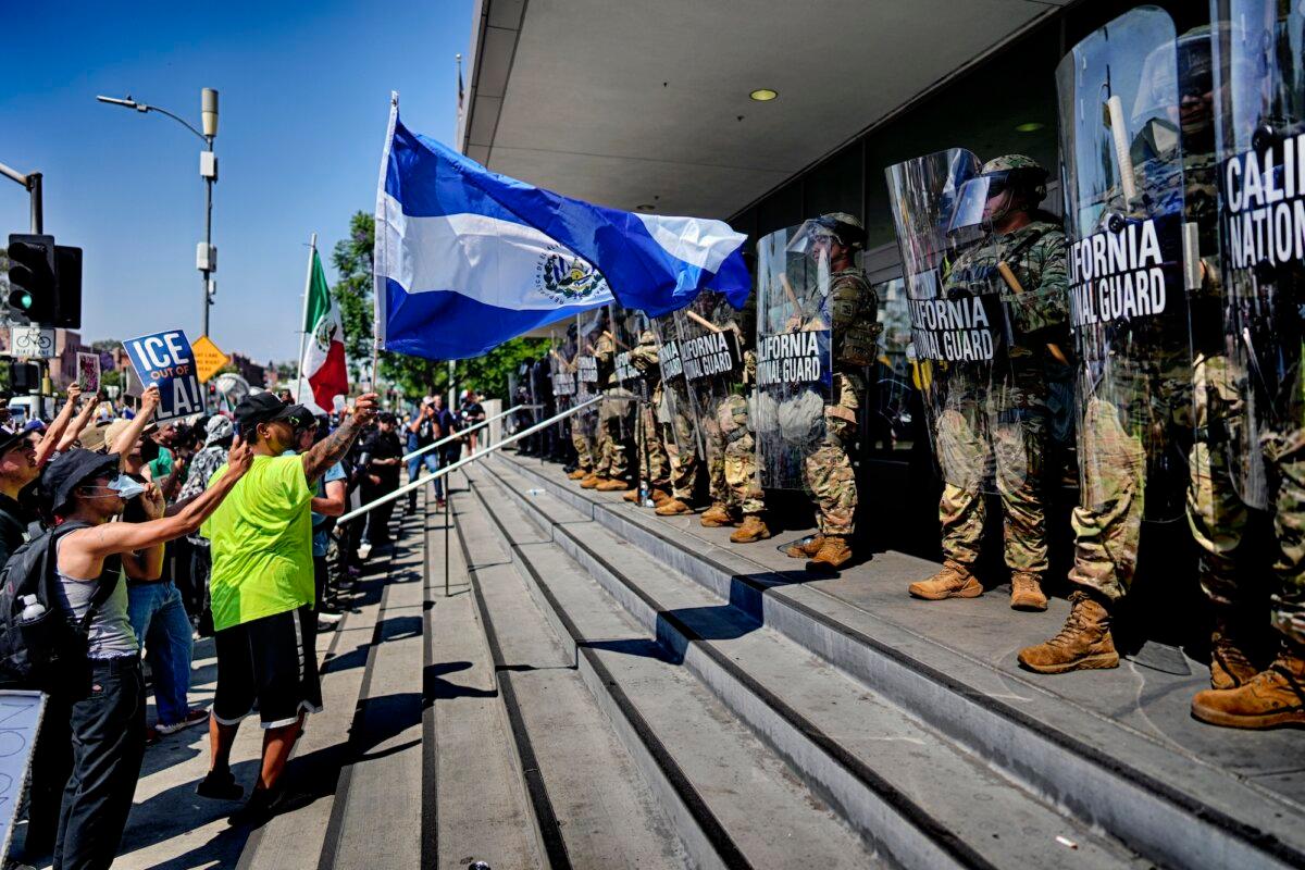 A protester waves the national flag of El Salvador in front of a line of California National Guard members in front of a federal building in downtown Los Angeles on June 9, 2025. (Eric Thayer/AP Photo)
