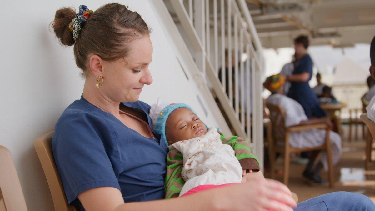A crew member aboard a Mercy Ship cares for a baby, in "The Mercy Ships." (Angel)