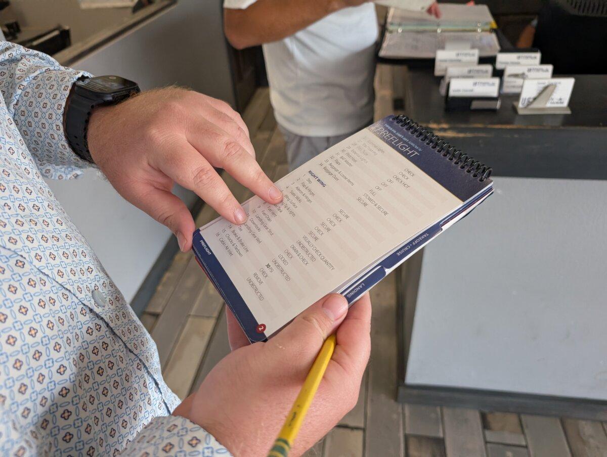 Jacob Kyser, 29, vice president and flight instructor at Universal Flight Training in Sarasota, Fla., shows an example of a pre-flight checklist on May 29, 2025. (Jacob Burg/The Epoch Times)