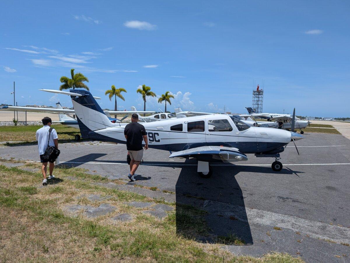 Justin Gorrell (L) and Aldo Costa (R), both flight instructors at Universal Flight Training in Sarasota, Fla., approach a Piper airplane ahead of a flight training session for Gorrell on May 29, 2025. (Jacob Burg/The Epoch Times)