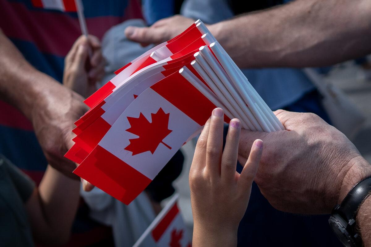 Un niño alcanza una bandera canadiense en el Día de Canadá en Vancouver, el 1 de julio de 2024. (The Canadian Press/Ethan Cairns)
