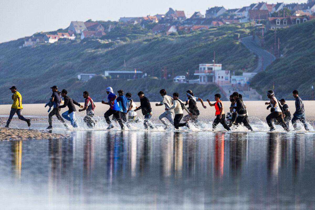 Migrants rush to board a smuggler's boat to cross the English Channel at the beach in Equihen, France, on June 30, 2025. (Sameer Al-Doumy/AFP via Getty Images)
