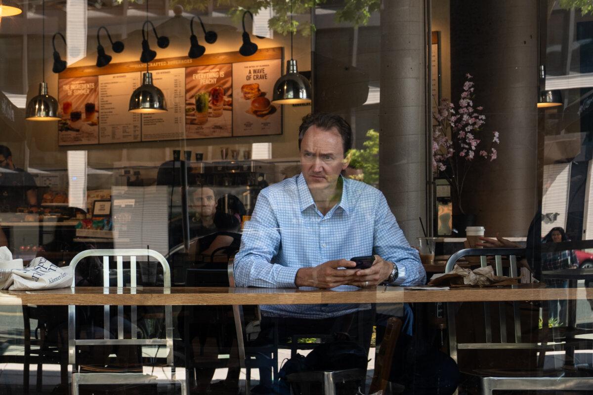 A man looks out the window at a coffee shop in Washington on July 1, 2025. (Madalina Kilroy/The Epoch Times)
