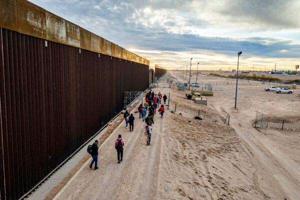 Illegal immigrants walk alongside the U.S.–Mexico border wall after crossing the Rio Grande into El Paso, Texas, on Feb. 1, 2024. (John Moore/Getty Images)