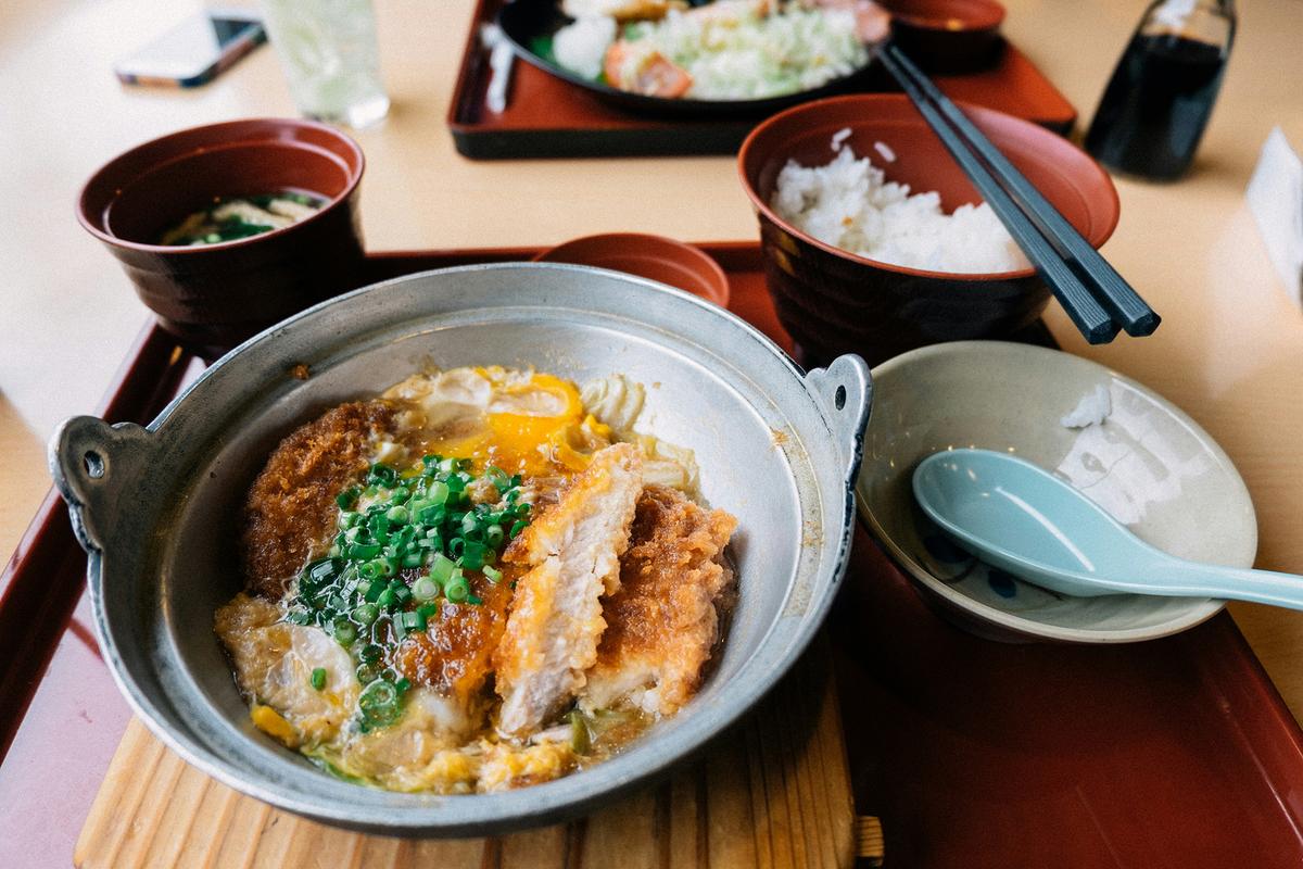 Katsudon is a beloved Japanese comfort food dish featuring a deep-fried, breaded pork cutlet topped with eggs and onion. It's often served over rice. (Tayawee Supan/Unsplash)