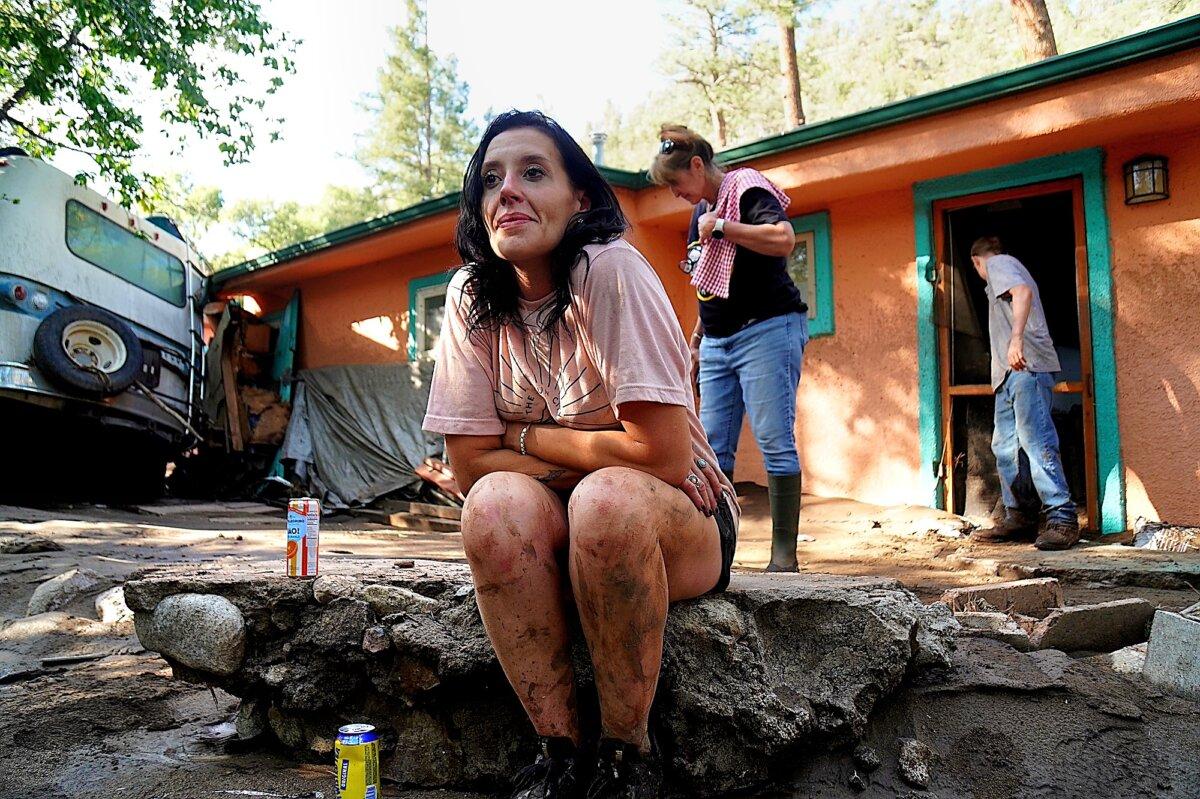Kalyn Sheffield sits outside her mother's house as her mother, Stephanie Sheffield, and her teenage son, Matthew, clean another property ruined by monsoonal floodwaters in Ruidoso, N.M., on July 8. (Allan Stein/The Epoch Times)