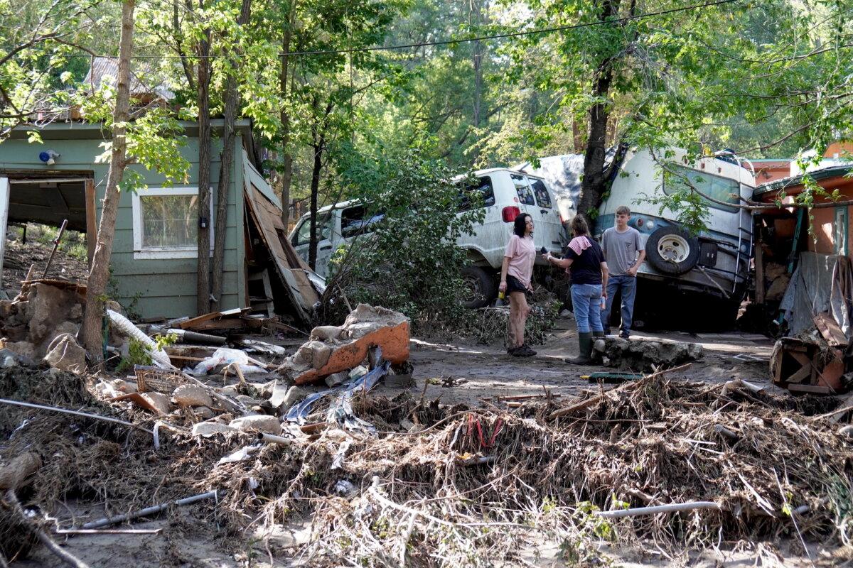 Kalyn Sheffield (L), her mother, Stephanie Sheffield, and son Matthew Sheffield, surrounded by debris near the Rio Ruidoso in the village of Ruidoso, N.M., on July 9, 2025. (Allan Stein/The Epoch Times)