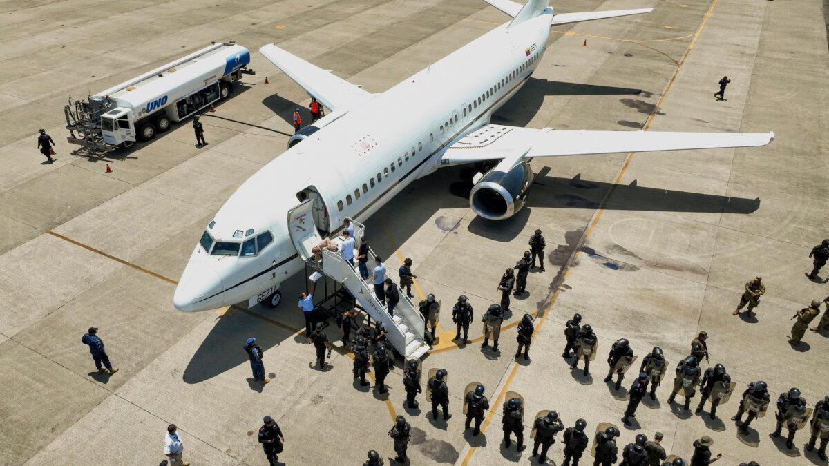 Men, who El Salvador's government identify as Venezuelans who the U.S. government detained and flew to El Salvador months ago, boarding a Venezuelan plane bound for Venezuela as soldiers stand by at the Oscar Arnulfo Romero International Airport in San Luis Talpa, El Salvador, on July 18, 2025. (El Salvador's presidential press office via AP)