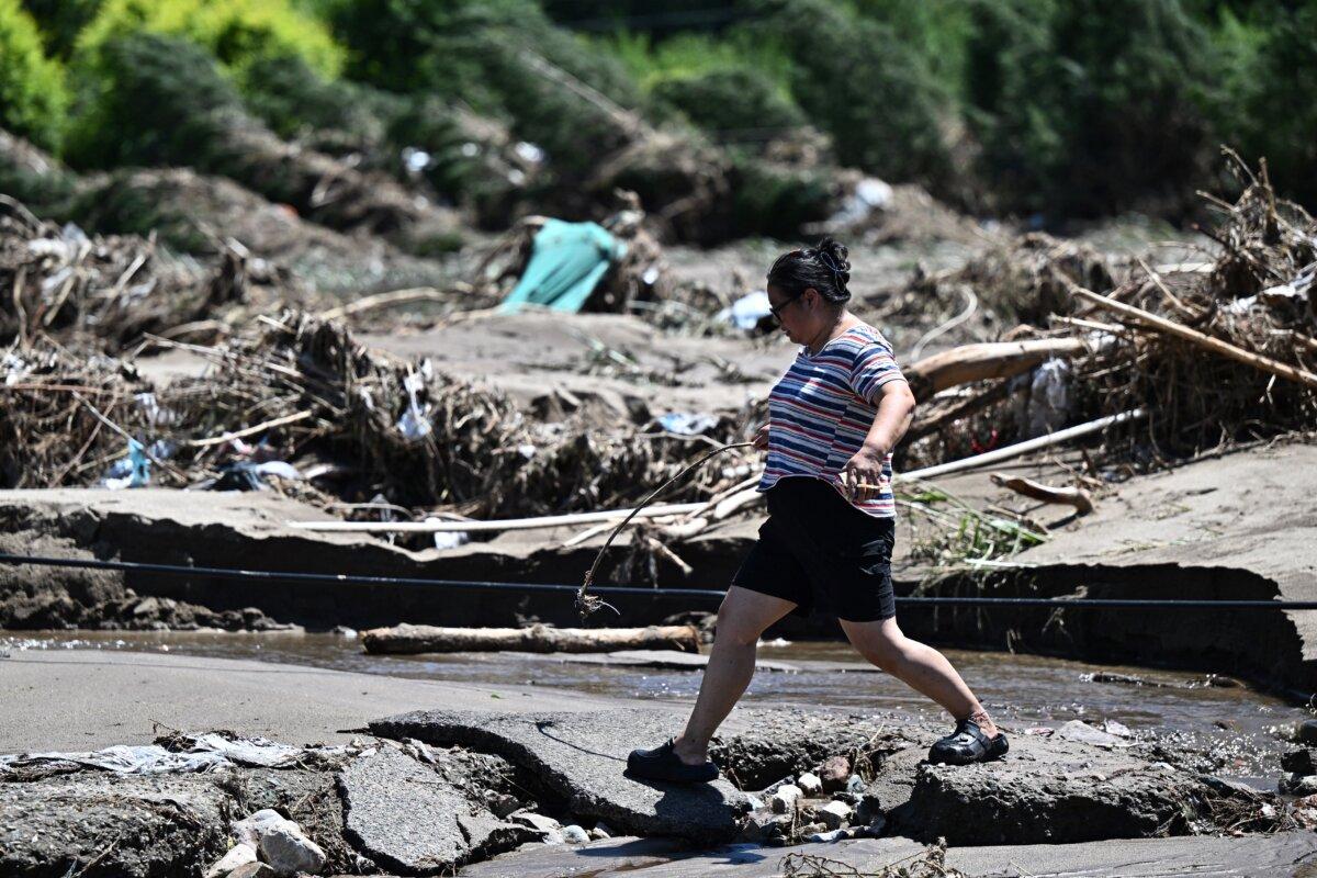 A woman walks past a flood-damaged area from heavy rains over the last few days in Huairou district, on the outskirts of Beijing on July 30, 2025. (Pedro Pardo/AFP via Getty Images)