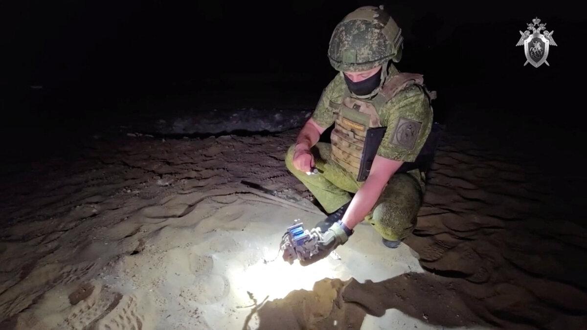 An officer of the Russian Investigative Committee examines remains of a drone on a beach following what local authorities said was a Ukrainian drone attack in Kursk, Russia, on July 9, 2025. (Russian Investigative Committee/Reuters)