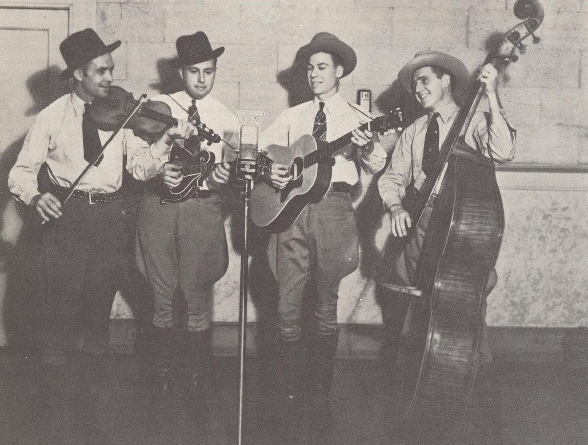 A photograph of Bill Monroe (2nd L) and the Blue Grass Boys from the 1976 album "Hills & Home; Thirty Years of Bluegrass." Internet Archive. (Public Domain)