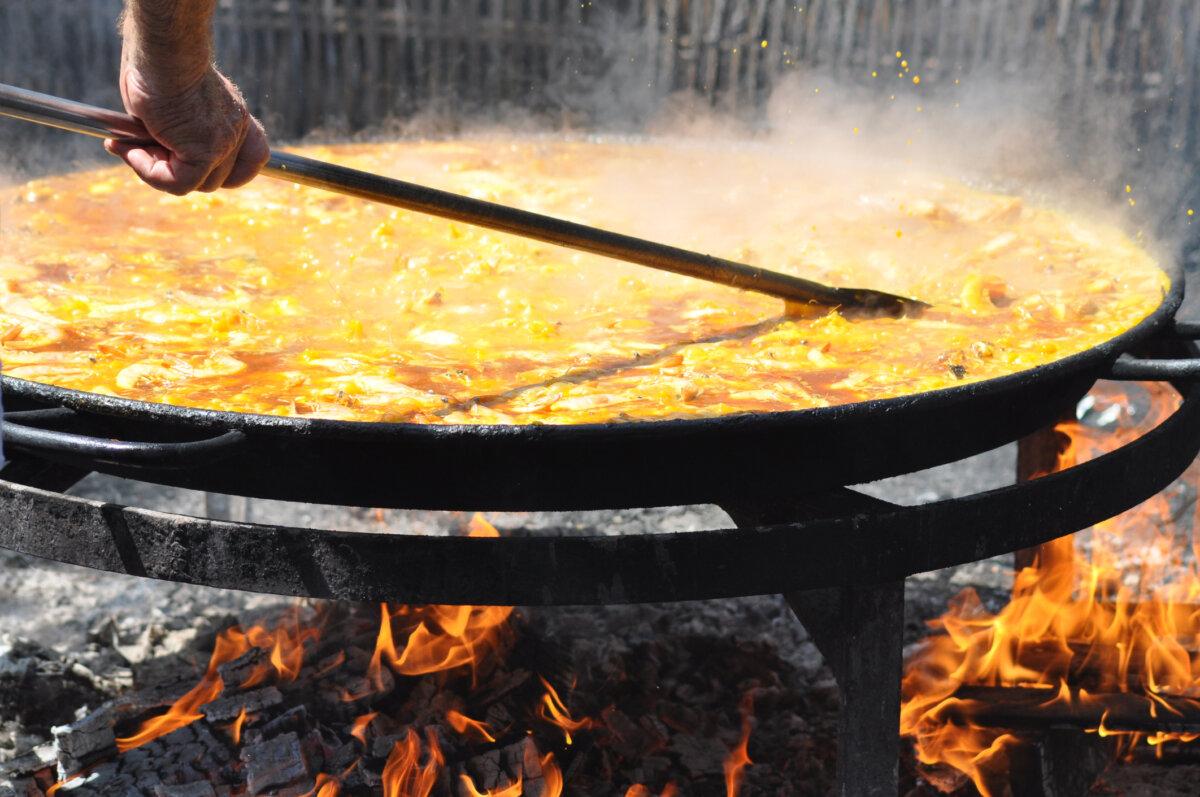 A man is cooking a huge paella, a Spanish traditional dish, at the beach (Nerja, Malaga) in the old-fashioned way. (Dreamstime/TCA)