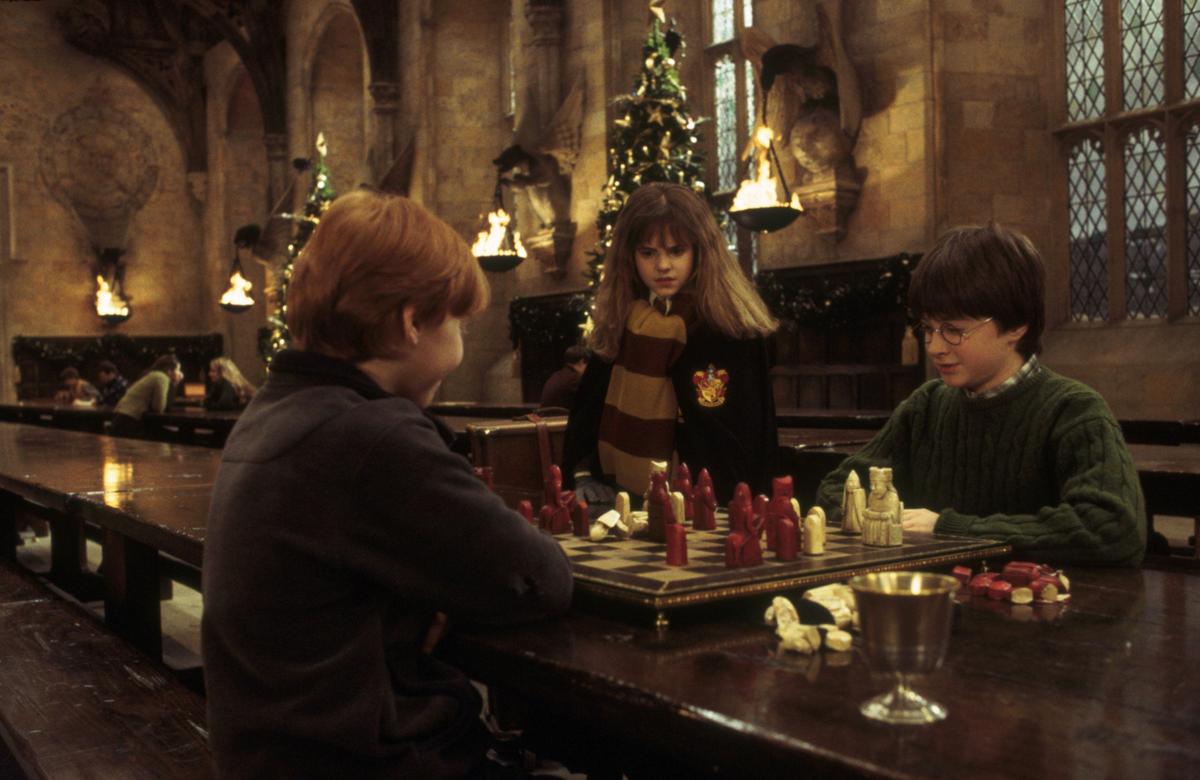 A publicity still from the 2001 film "Harry Potter and the Sorcerer's Stone" featuring (L–R) Ron Weasley, Hermione Granger, and Harry Potter playing chess on a Lewis Chessmen set. (MovieStillsDB)