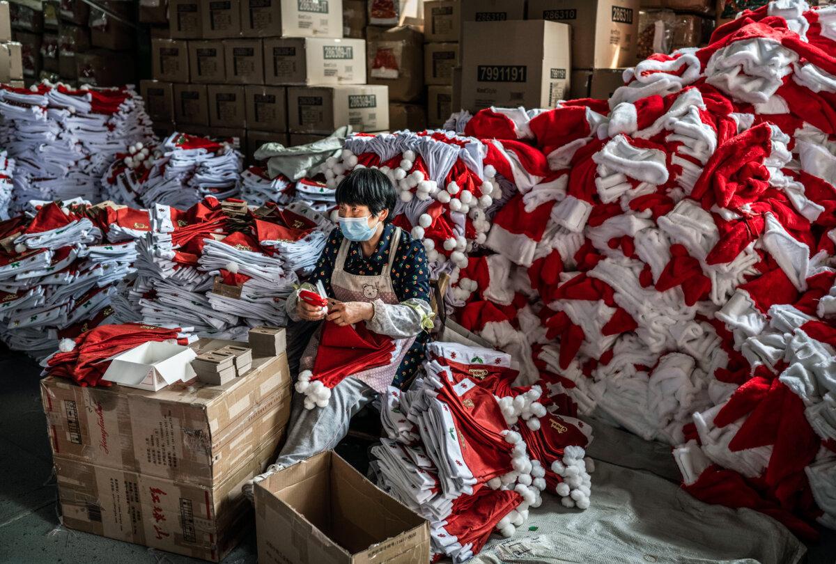 A worker puts tags on red Santa Claus hats for export at a factory near Yiwu, Zhejiang Province, China, on April 28, 2025. (Kevin Frayer/Getty Images)