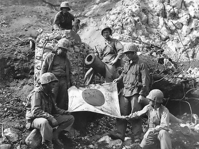 U.S. Marines pose with a captured Japanese flag on top of enemy pillbox at Iwo Jima. National Park Service. National Archives, USMC. (Public Domain)