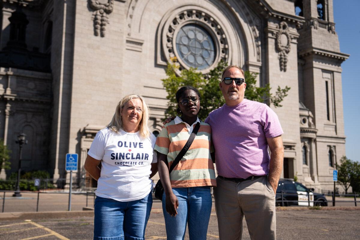 <span style="font-weight: 400;">Lanae Pearson</span> (L) and Mark Pearson (R), with their adopted daughter from Ghana, Josephine Pearson (C), visit the Cathedral of Saint Paul, in Saint Paul, Minn., on Aug. 28, 2025. (Madalina Kilroy/The Epoch Times)