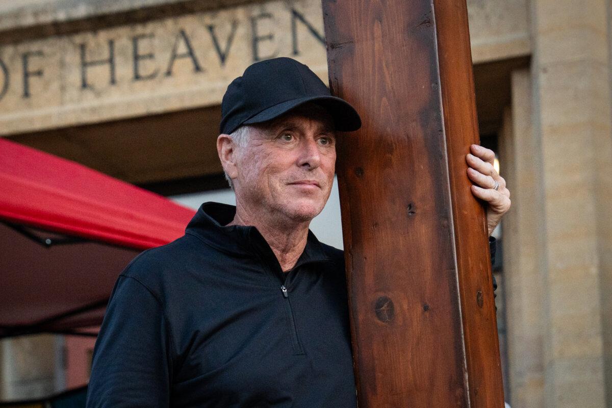 Dan Beazley drove 11 hours from his home in Detroit to bring his 10-foot-tall, 65-pound cedar cross to the Annunciation Catholic community shooting scene in Minneapolis on Aug. 28, 2025. (Madalina Kilroy/The Epoch Times)