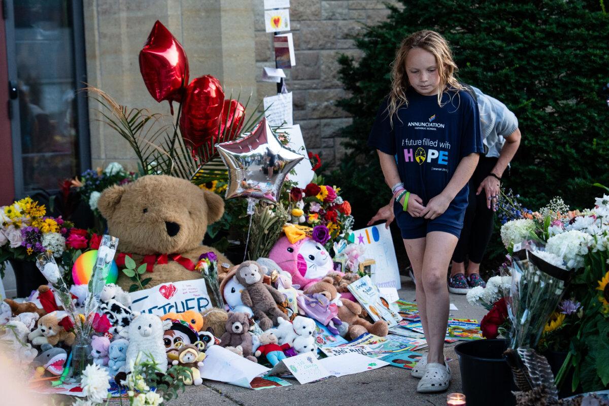 Paying respects to the two schoolchildren who were killed in a shooting, mourners visit a makeshift memorial at Annunciation Catholic Church in Minneapolis on Aug. 28, 2025. (Madalina Kilroy/The Epoch Times)