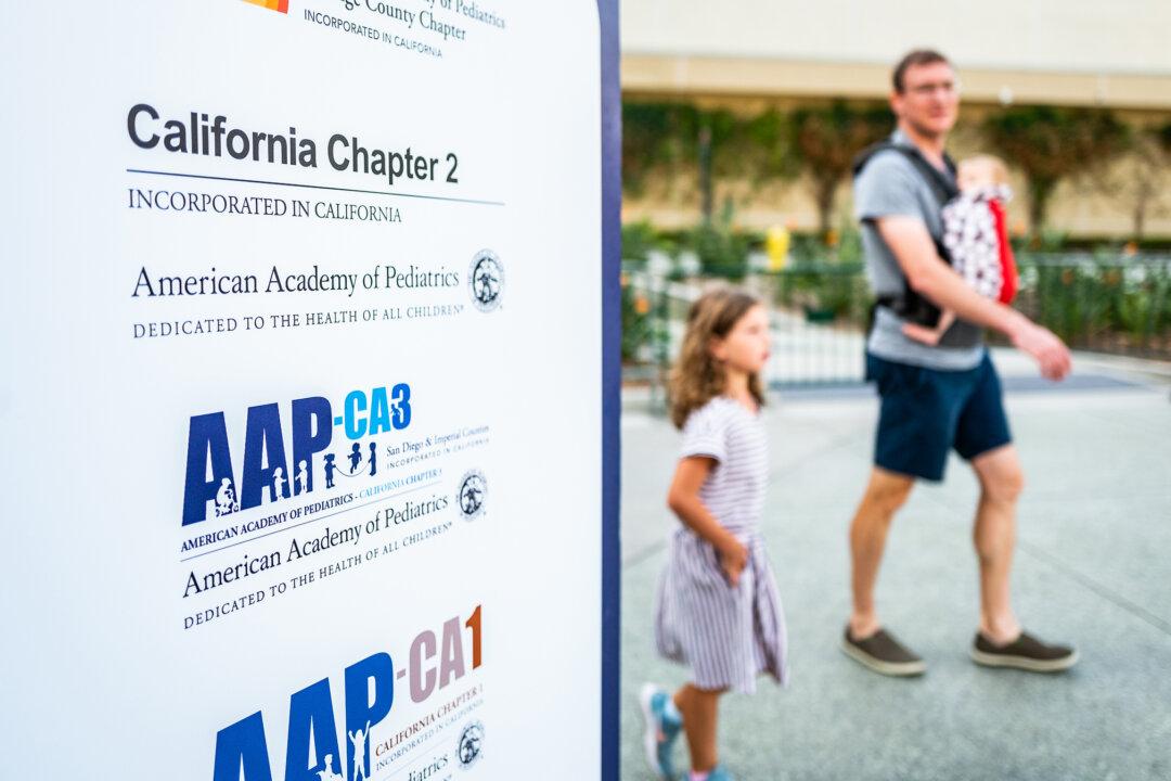 People walk past a sign for an American Academy of Pediatrics (AAP) conference in Anaheim, Calif., on Oct. 8, 2022. (John Fredricks/The Epoch Times)