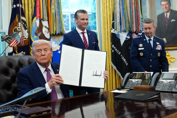 President Donald Trump displays a signed executive order renaming the Department of Defense to the Department of War as U.S. Defense Secretary Pete Hegseth (C) and Chairman of the Joint Chiefs of Staff Air Force Gen. Dan Caine (R) look on in the Oval Office of the White House on Sept. 5, 2025. (Kevin Dietsch/Getty Images)