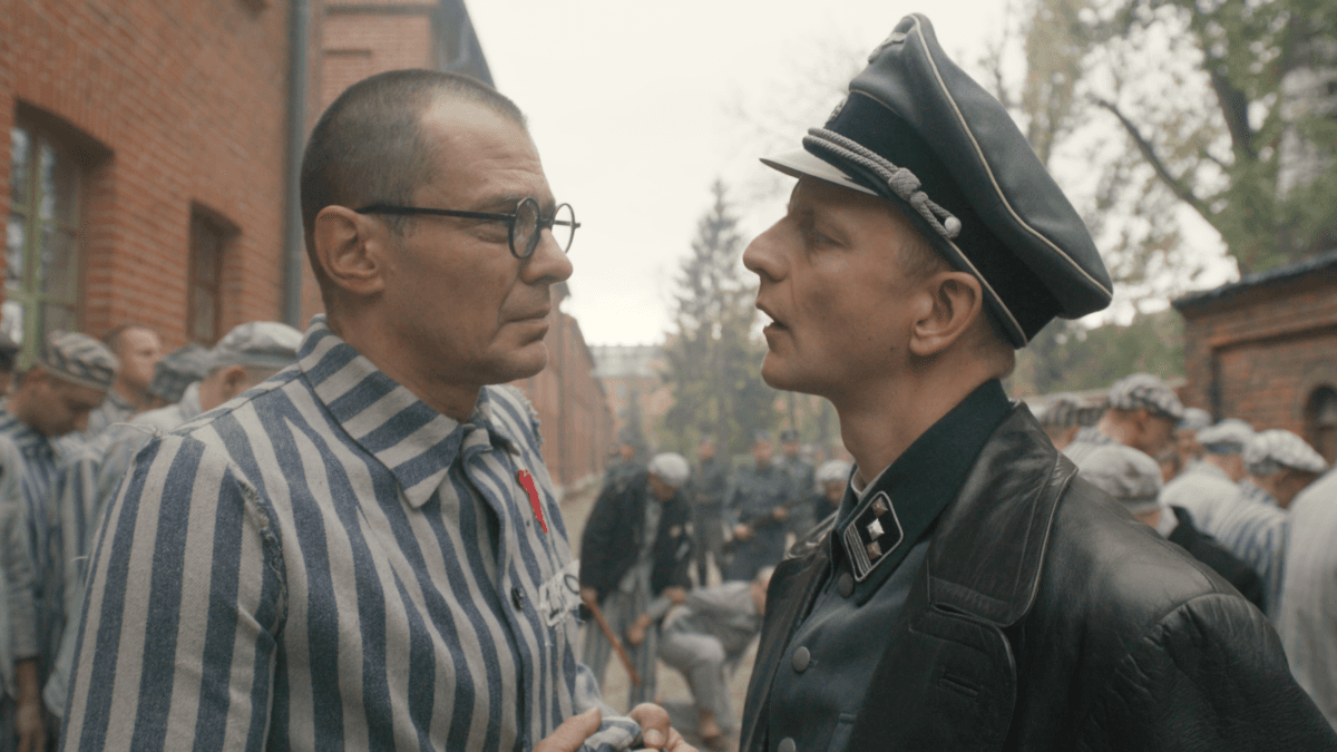 Father Maximilian Kolbe (Marcin Kwasny, L) is questioned by SS commandant Karl Fritzsch (Christopher Sherwood), in “Triumph of the Heart.” (Sherwood Fellows)