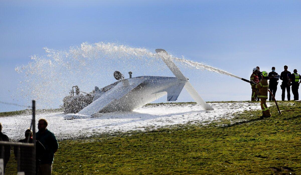 Firemen direct foam onto a light plane after it crashed in Melbourne, Australia, on June 22, 2021. (William West/AFP via Getty Images)
