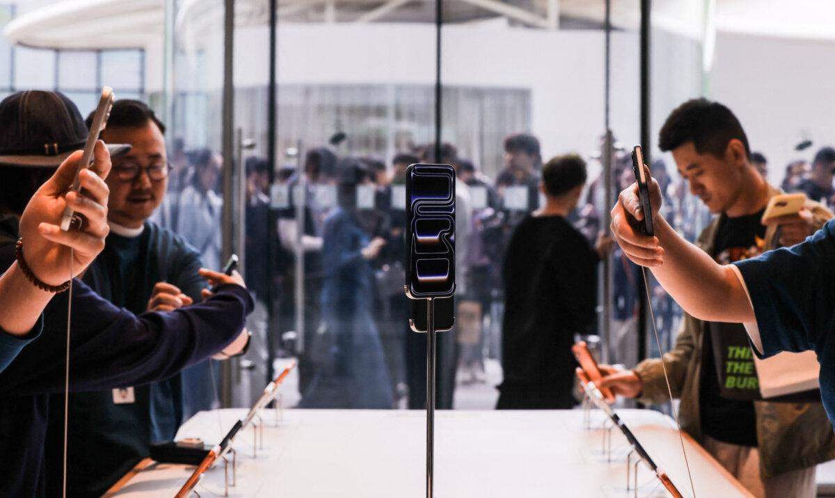 People try the new iPhone 17 series smartphones at an Apple store as a line is seen outside during the start of sales, in the Sanlitun area of Beijing on Sept. 19, 2025. (Maxim Shemetov/Reuters)
