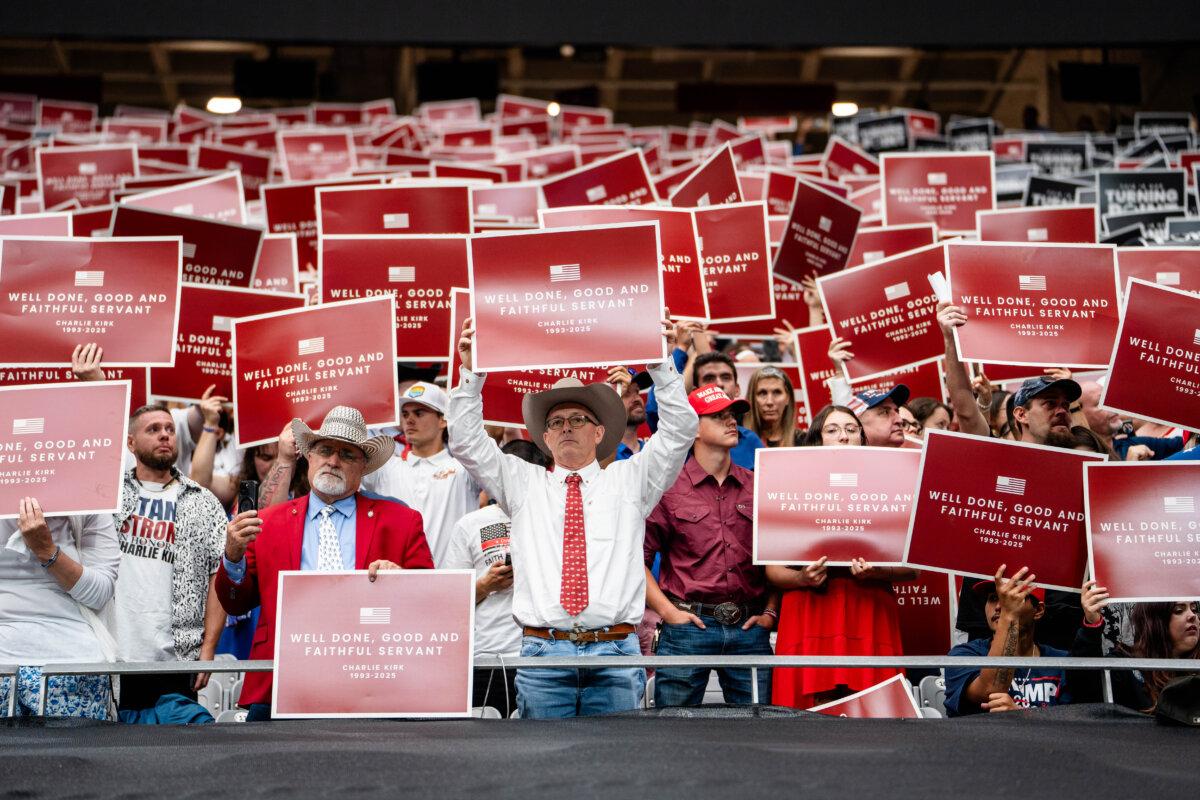 People hold signs as they take part in the Building a Legacy: Remembering Charlie Kirk Memorial event at the State Farm Stadium in Glendale, Ariz., on Sept. 21, 2025. (Madalina Kilroy/The Epoch Times)