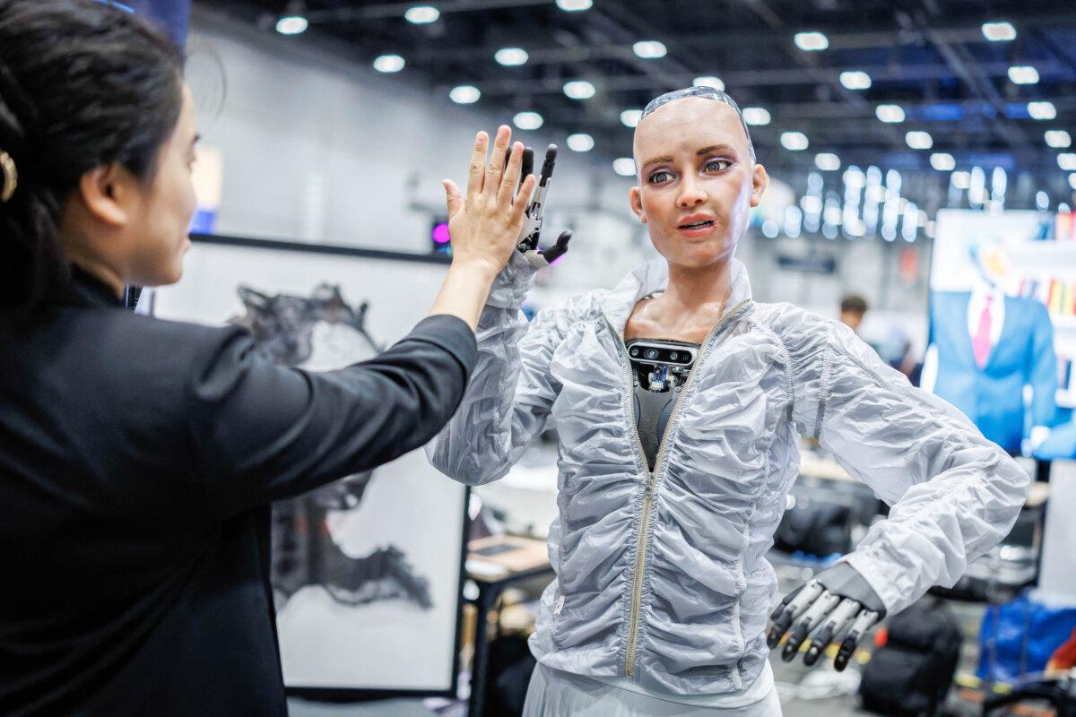 Sophie, a robot using artificial intelligence from Hanson Robotics, shares a high five with a visitor during the International Telecommunication Union AI for Good Global Summit in Geneva, on July 8, 2025. (Valentin Flauraud/AFP via Getty Images)