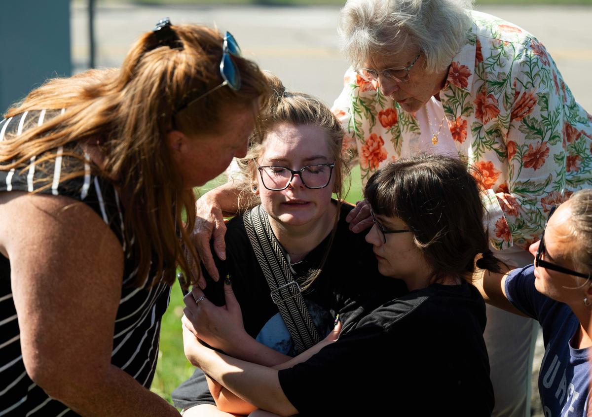 Joanne Green, 75, of Fenton (2nd R) and McKenna Harrington, 25, of Davison (3rd R) comfort Katelyn Kruse, 26, of Fenton (C) after Kruse was present at the scene of a shooting and structure fire at the Church of Jesus Christ of Latter-day Saints on McCandlish Road in Grand Blanc, Mich., Sept. 28, 2025. (Katy Kildee/Detroit News via AP)