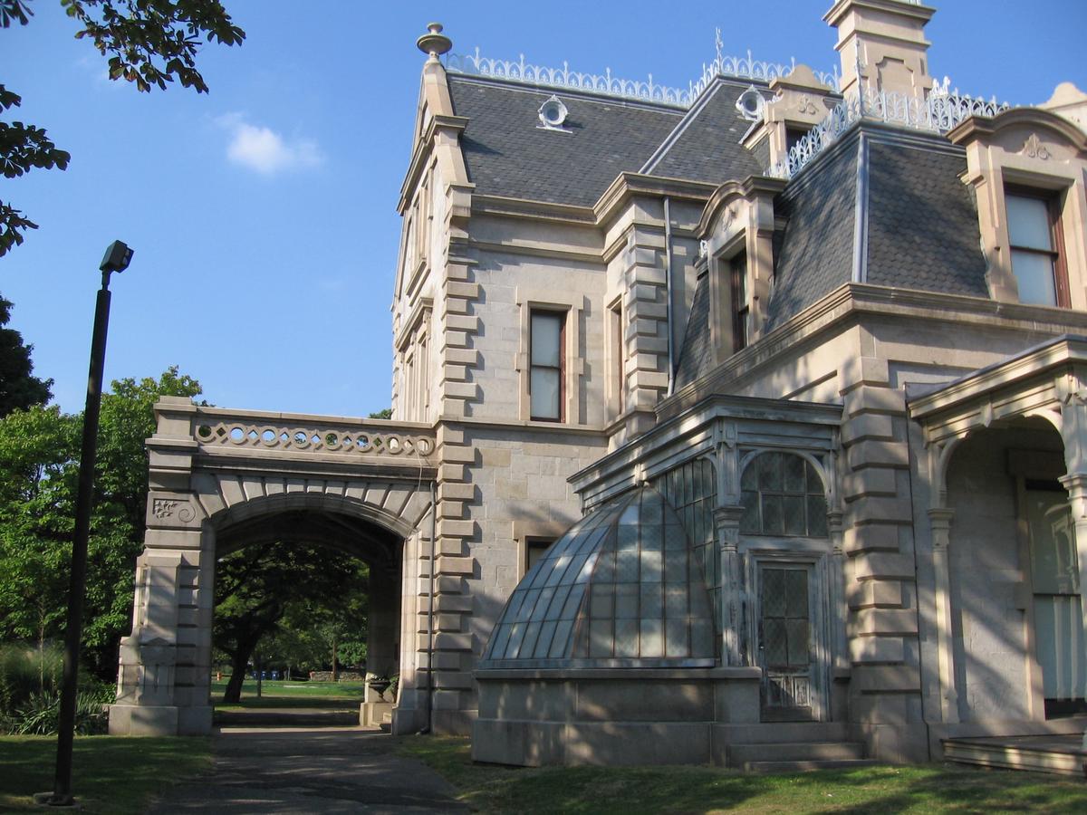 On the west side of the Lockwood-Mathews Mansion is the porte cochere, or covered carriage gate, where visitors enter the home through the groin-vaulted vestibule. The conservatory, with its ribbed glass half-dome, is an excellent example of early Gilded Age greenhouse architecture. (<a class="extiw" title="en:User:Noroton" href="https://en.wikipedia.org/wiki/User:Noroton">Noroton</a>/<a href="https://creativecommons.org/licenses/by-sa/3.0/deed.en">CC BY-SA 3.0</a>)