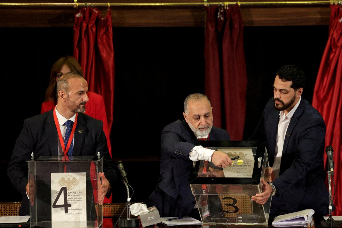 A member of electoral colleges opens the ballot box, during a vote to select a candidate for the new Syrian Parliament since Bashar al-Assad's government was toppled, in Damascus, Syria, on Oct. 5, 2025. (Khalil Ashawi/Reuters)