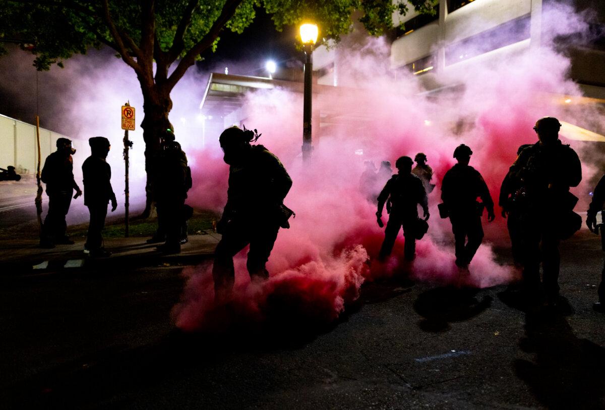 Federal officers deploy smoke grenades to deter protesters in front of Immigration and Customs Enforcement offices in Portland, Ore., on Oct. 5, 2025. (John Fredricks/The Epoch Times)