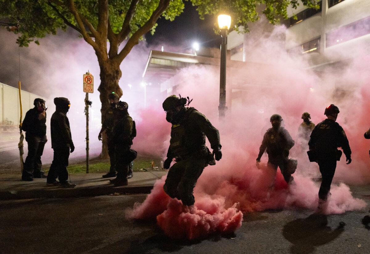 Federal officers deploy smoke grenades to deter protestors in front of Immigration and Customs Enforcement offices in Portland, Oregon, on Oct. 5, 2025. (John Fredricks/The Epoch Times)