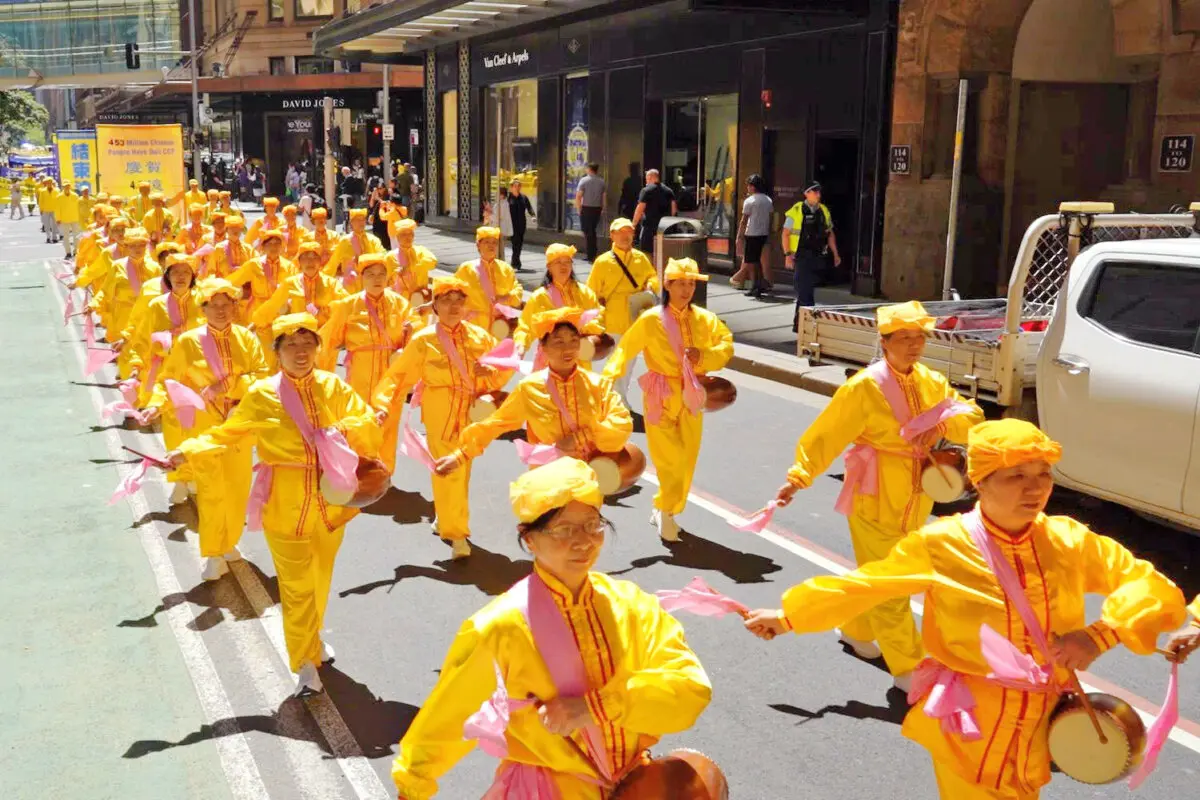 Falun Dafa practitioners dressed in traditional Chinese waist drum costumes perform during a parade through Sydney's busy CBD in Australia, on Oct. 10, 2025. (Wang Nan/NTD TV)
