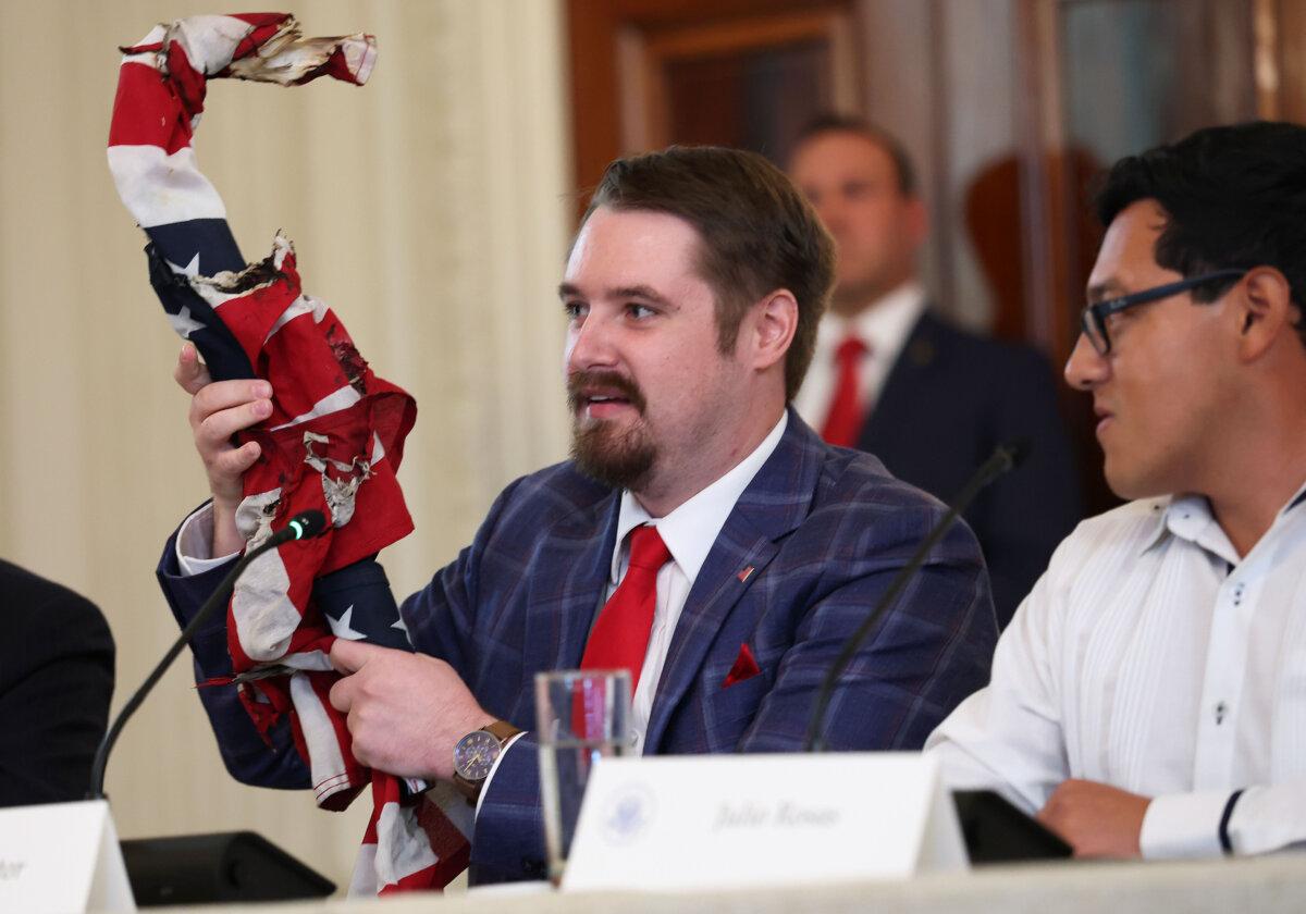 Conservative influencer Nick Sortor holds up an American flag recovered from protests in Portland, Ore., during a roundtable discussion in the State Dining Room of the White House on Oct. 8, 2025. (Anna Moneymaker/Getty Images)
