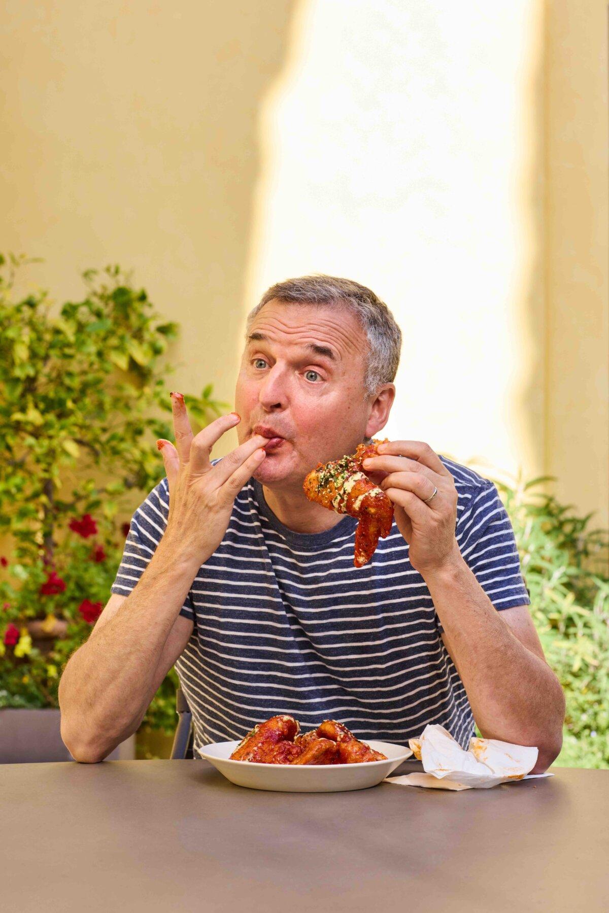 Rosenthal feasts on Korean Fried Chicken Wings. He features the recipe from chef Angel Barreto of Anju in Washington in his latest cookbook, “Phil’s Favorites.” (Andrea D’Agosto)