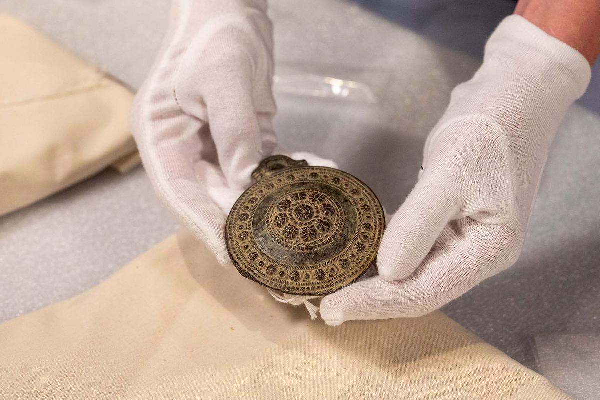 A staff member at Simon Fraser University holds the larger of two medallions believed to hail from medieval times that were found in a B.C. thrift store. (Courtesy of Simon Fraser University)