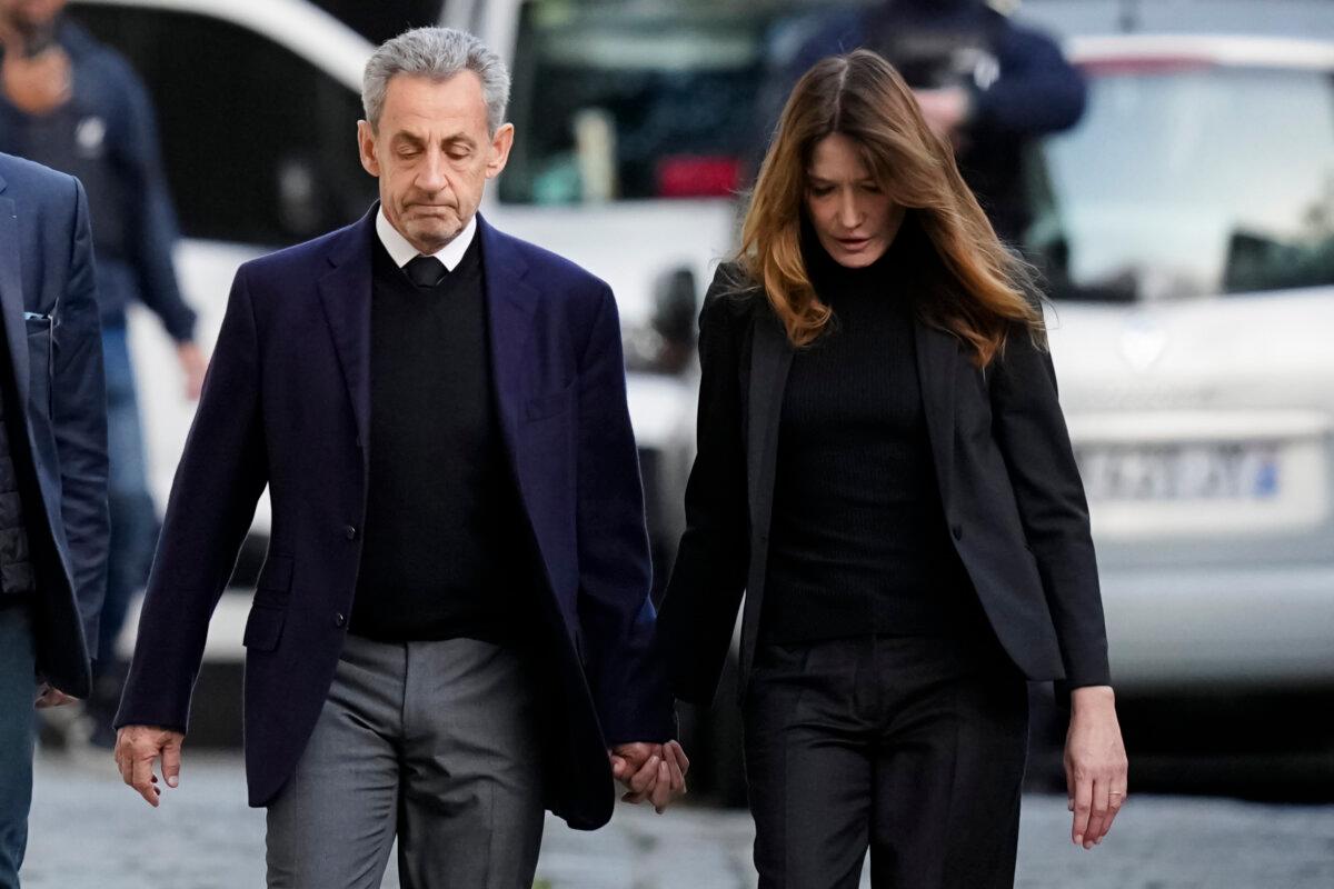Former French President Nicolas Sarkozy and his wife, Carla Bruni-Sarkozy, leave their home as Nicolas Sarkozy heads to prison to serve time for a criminal conspiracy to finance his 2007 election campaign with funds from Libya, in Paris on Oct. 21, 2025. (Thibault Camus/AP)