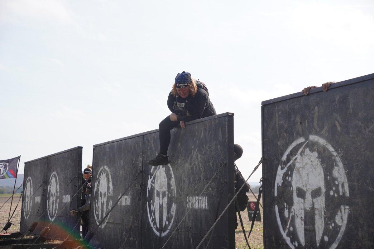 Runner climbs a wall obstacle at the 2025 Tri-State New York Spartan Event Weekend in the Town of New Hampton, N.Y., on Oct. 19, 2025. (Oliver Mantyk/The Epoch Times)
